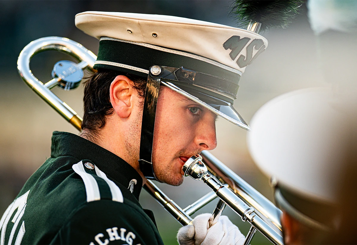 a marching band student wearing a uniform holding his trumpet