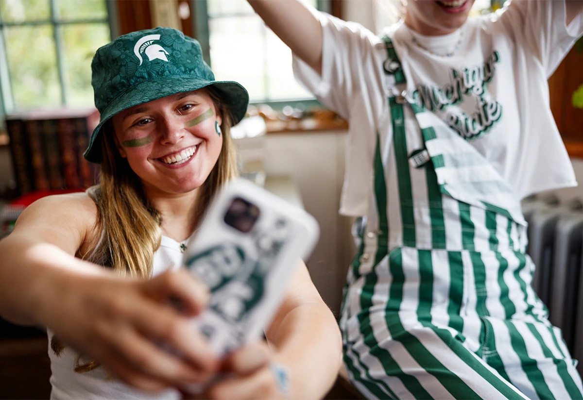 three friends dressed up in green and white fan gear while taking a selfie