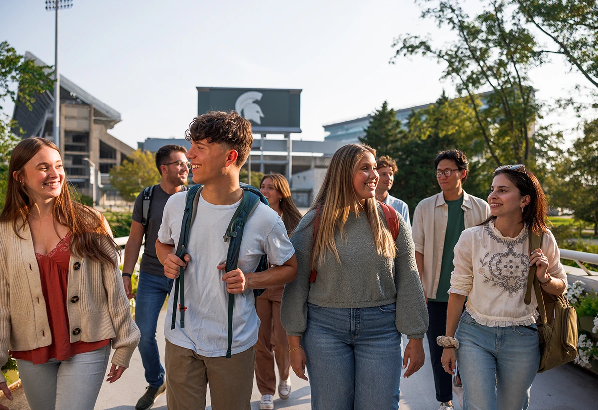 students walk by the stadium on a sunny day